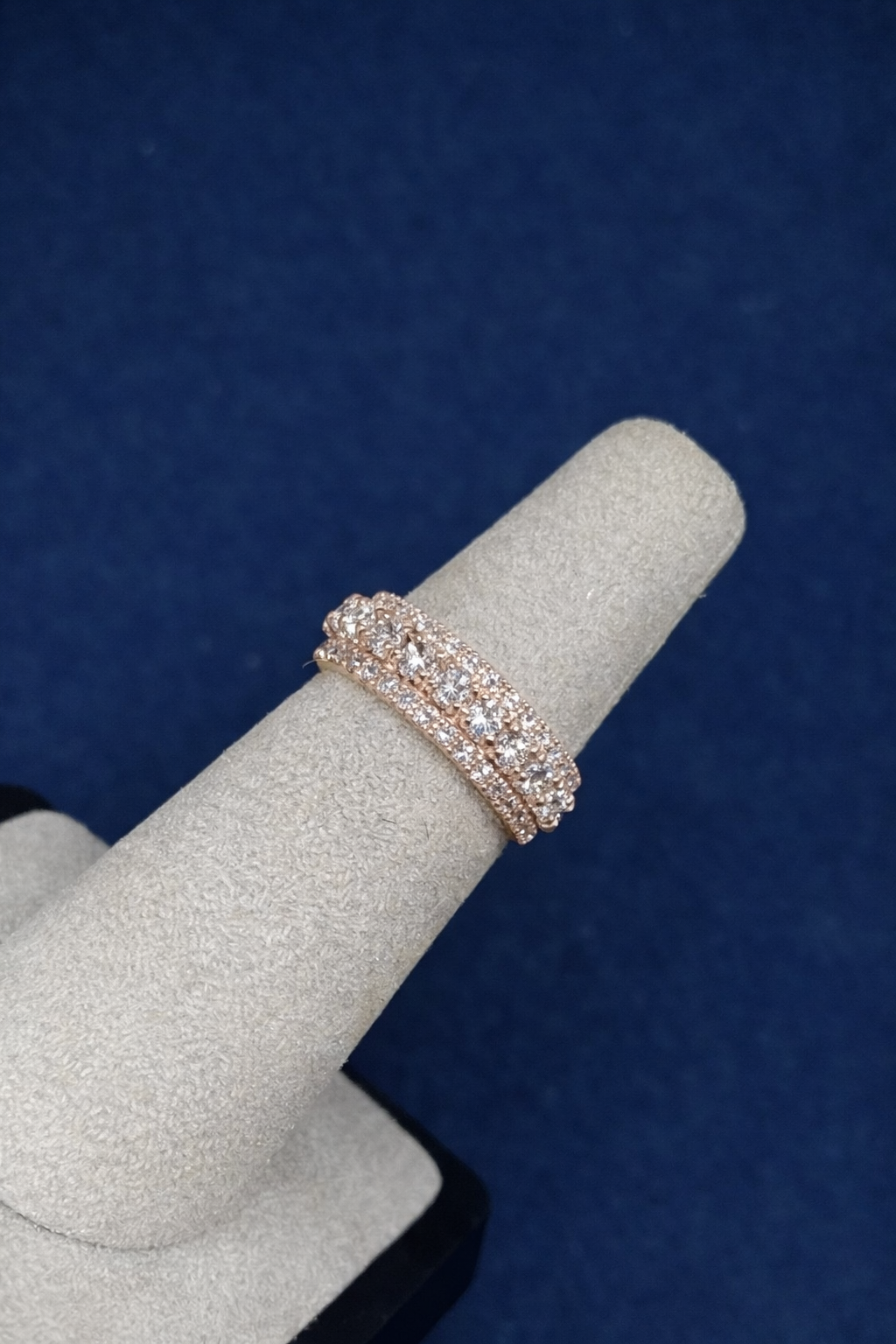 Custom double-band infinity ring set with moissanite, worn on a grey display cone against blue velvet