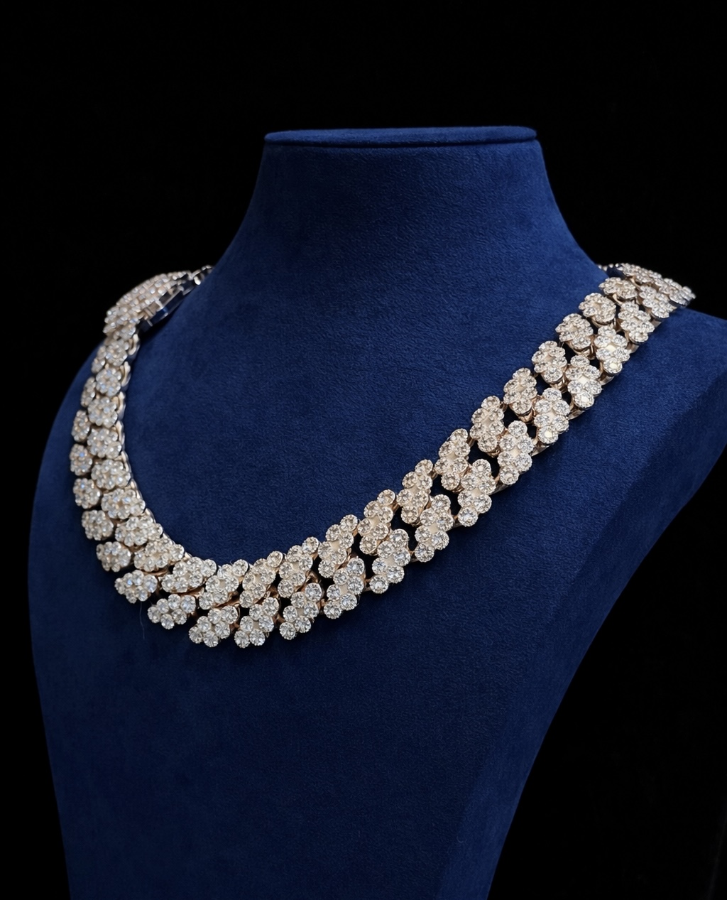 Iced out Cuban link chain on a blue velvet display bust